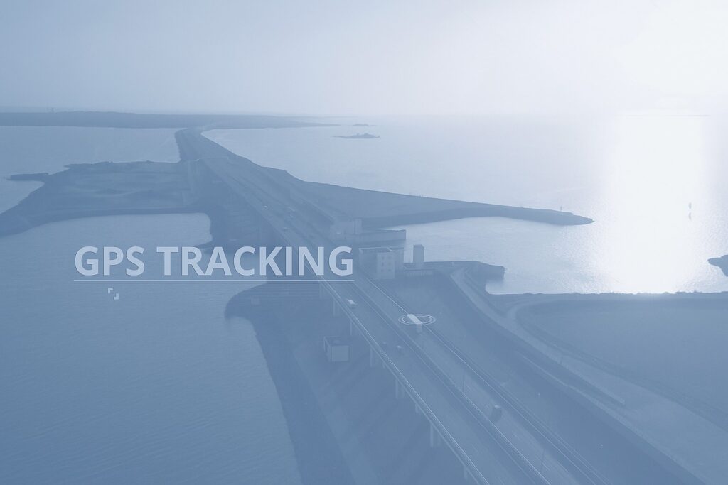 Aerial view of a long highway bridge over water at sunset with GPS TRACKING text overlay