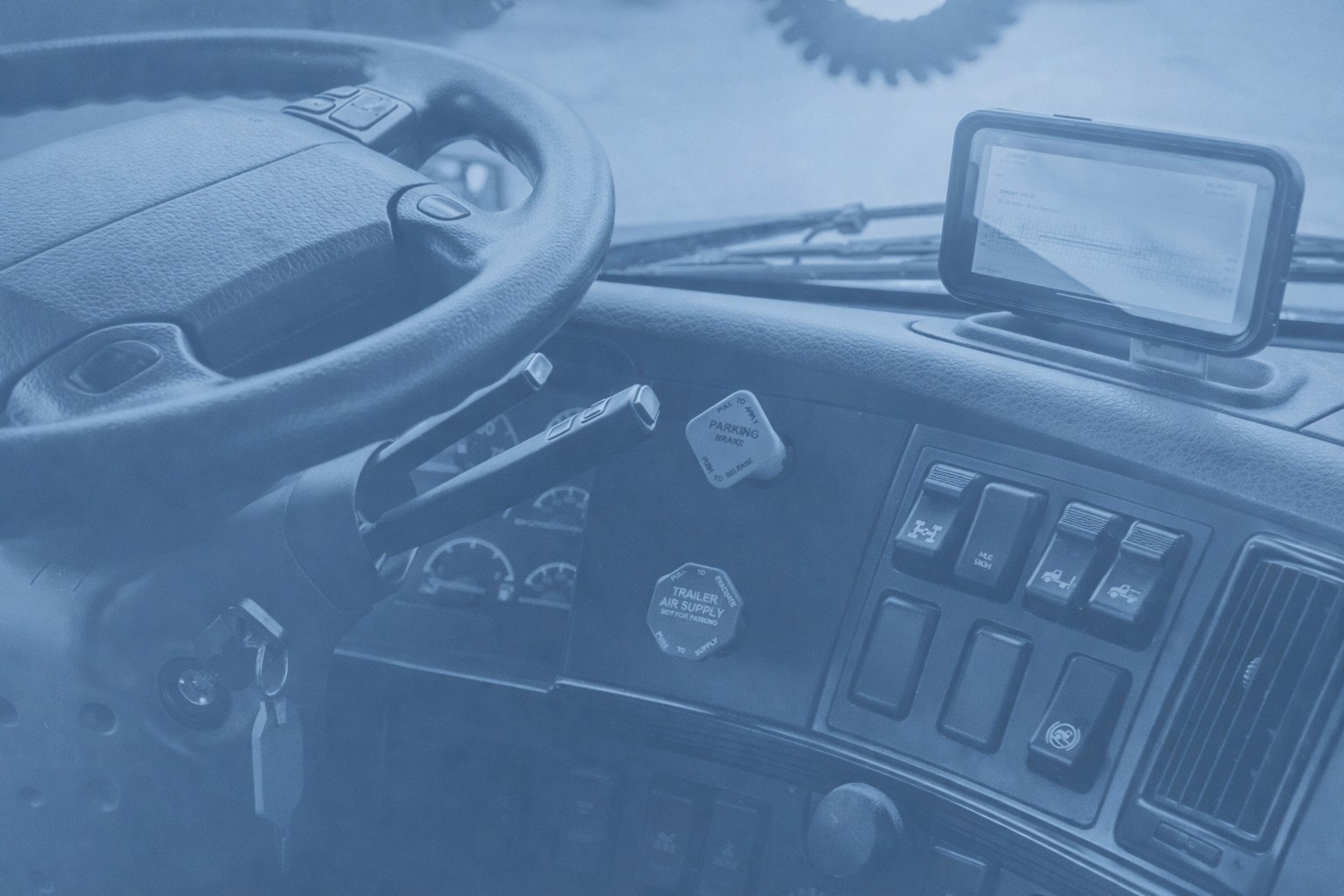 Truck dashboard with steering wheel, electronic log device, and control switches under blue filter overlay